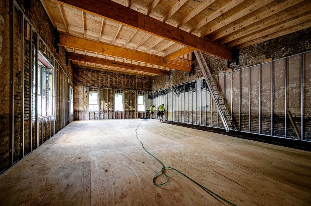 Open room with exposed beams and framed walls under renovation